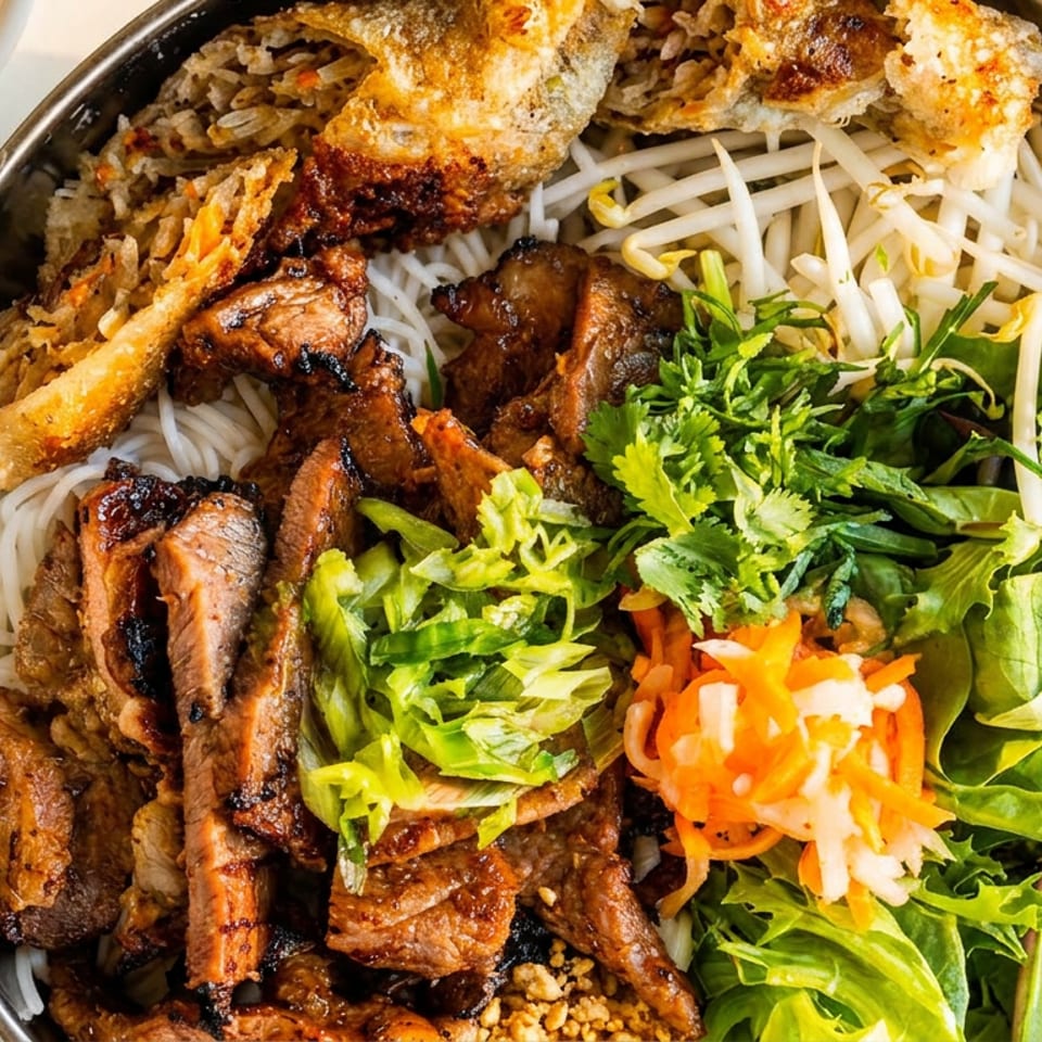 Vietnamese rice noodle bowl with grilled meat, crispy spring rolls, bean sprouts, herbs, greens, and pickled vegetables.