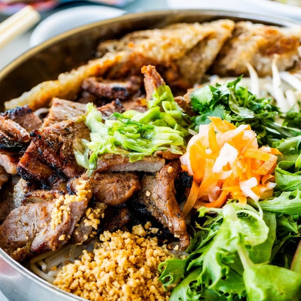 Vietnamese vermicelli bowl topped with grilled beef, fried spring rolls, fresh greens, herbs, pickled carrots, and crushed peanuts.